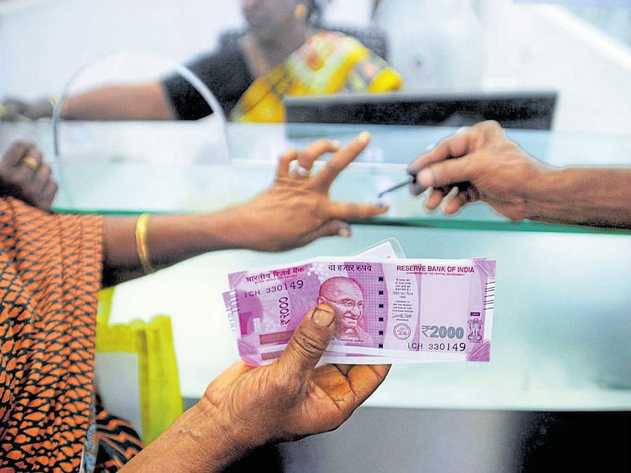 A woman holds her Rs 2,000 notes as she has her finger marked with indelible ink after exchanging demonetised notes at a bank in Chennai on Thursday. AFP