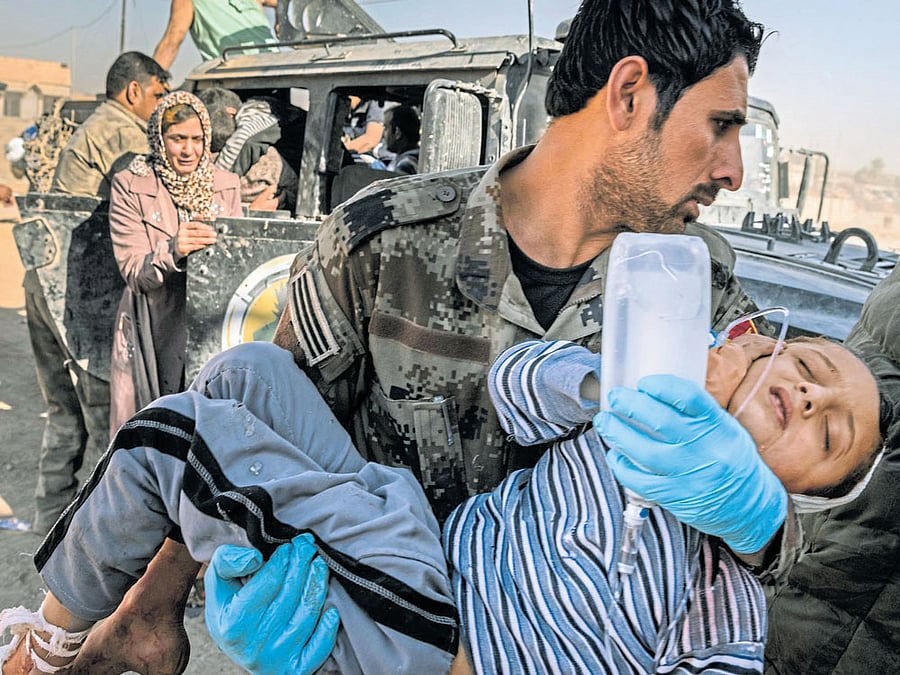collateral damage: A medic carries a child wounded during fighting to a field hospital on the outskirts of Mosul. An Iraqi govt order imploring civilians to stay in their homes while the battle to regain the city raged, has cost them dearly. NYT