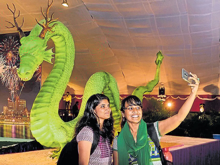 Visitors take a selfie in front of Chinese Dragon cake (14 ftX 4 ft), made of sugar, at the 42nd  annual cake show at St Joseph's Indian High School grounds in Bengaluru on Friday. dh photo