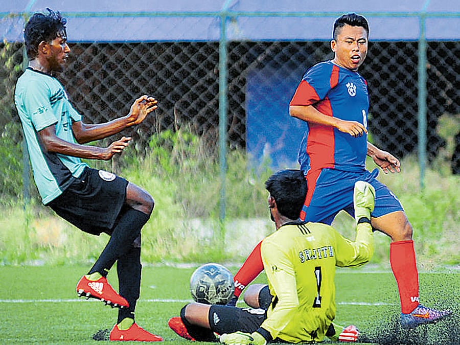 South United goalkeeper Srijith (centre) thwarts an attempt from MEG foward Christopher (right) in the BDFA Super Division league on Monday. DH Photo