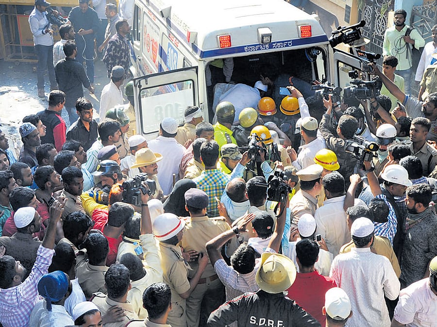 Firemen shift a body to an ambulance after a fire broke out in a four-storey building at Vinayakanagar in Old Guddadahalli at J J Nagar off Mysuru Road in Bengaluru on Friday