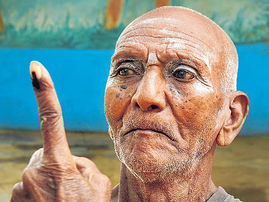 94-year-old Madegowda shows his index finger after casting his vote.