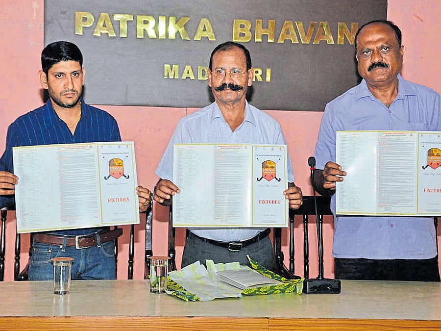 Sampath of Biddatanda Hockey Namme technical committee, ground committee president Biddatanda Belliappa and Kodava Sahitya Academy president B S Thammaiah release the fixtures of the tournament at Madikeri Press Club on Tuesday.
