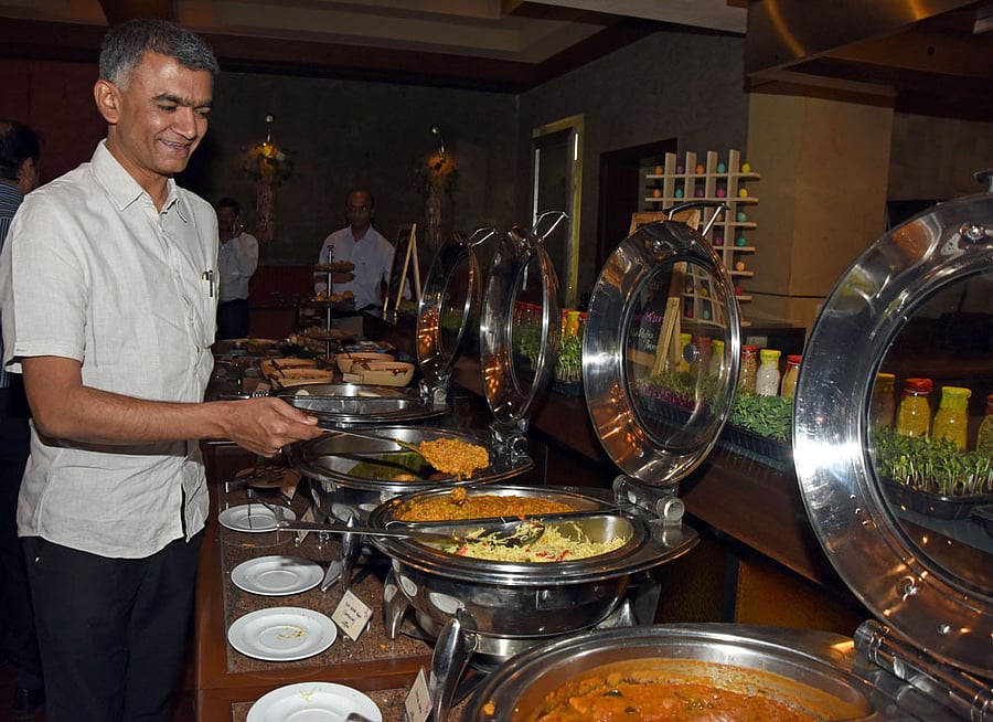 Agriculture Minister Krishna Byre Gowda helps himself to bisi bele bath made of millets at an event organised in Bengaluru on Thursday to announce the 'Organics and Millets 2017 - National Trade Fair' that will be held from April 28 to 30 in the city. DH&#8200;Photo