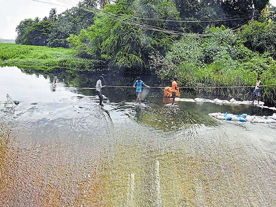 Workers put sandbags to prevent foaming in Bellandur lake on Tuesday. dh Photo