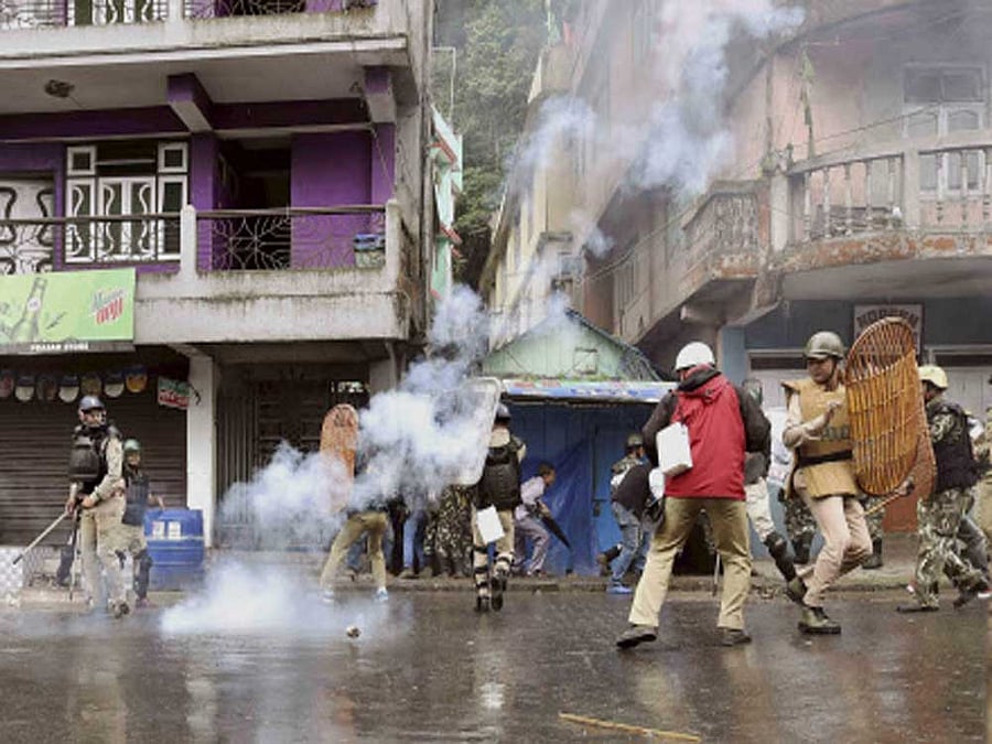 Security personnel retreat during a protest by Gorkha Janmukti Morcha (GJM) activists in Darjeeling on Saturday. PTI Photo
