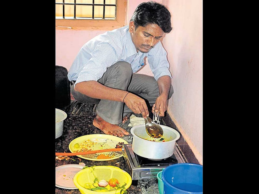 Mechanical engineer Shivanand Kalabanura cooks a puffed rice dish during the practical exam for the post of cooks in BCM hostels in Bagalkot on Monday. DH Photo