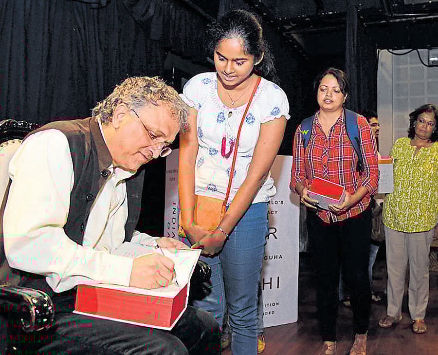 Historian Ramachandra Guha signs autographs on the 10th anniversary edition of his book 'India After Gandhi,' which was released on Friday. DH Photo