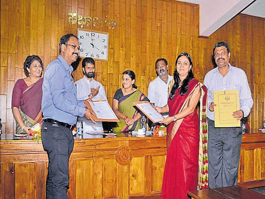 CMC Commissioner M V Tusharamani and Afsar Ahmmed Mohammed of ITC exchange MoU, in Chikkamagaluru on Monday. DC Satyavathi, MLA C T Ravi, CMC President Kavitha Shekar and Vice President Ravindra Prabhu look on.