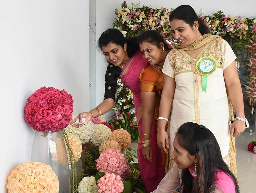 Women admire flowers on display at a function organised to open a flower exhibition centre and a training facility in Bengaluru on Monday. DH photo