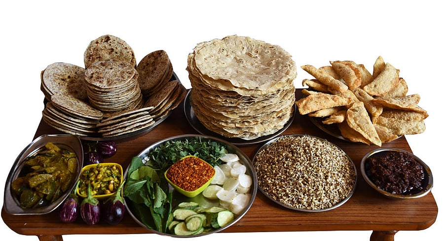 The thali in Dharwad has fluffy, soft jowar roti along with curries like badnekayi enagayi, chutneys, jhunkad wadi, pudi, menthe soppu, salad, and rice with curds.