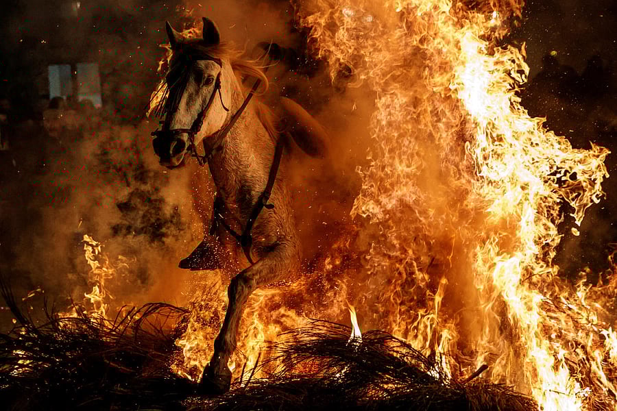 A man rides a horse through flames during Luminarias celebration. REUTERS