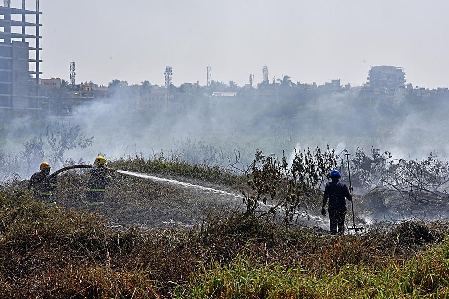 Fire men spray water to extinguish a fire broken out from the Bellandur lake which cot fire, in Bengaluru on Saturday. Photo by S K Dinesh
