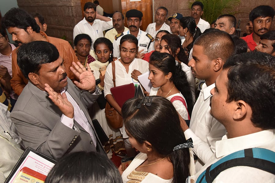 Students gherao Prof Shivaraju, Registrar (Evaluation), demanding gold medals, on Thursday. DH Photo/S K Dinesh
