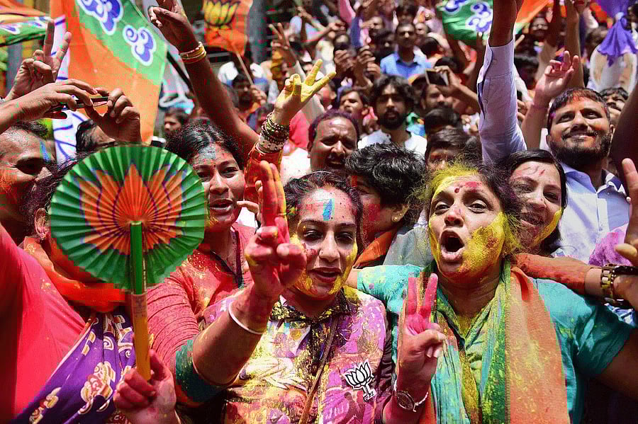 BJP workers celebrate with colours the party's lead on more than 110 Assembly seats, as the counting of votes is in progress, outside the party office in Bengaluru on Tuesday. PTI Photo