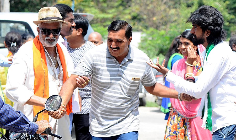 Both BJP and JDs workers pulling one of the voter's hand to cast their votes to their party's outside the pooling booth at Rajarajeswari nagar in Bengaluru on Monday. Photo Srikanta Sharma R.