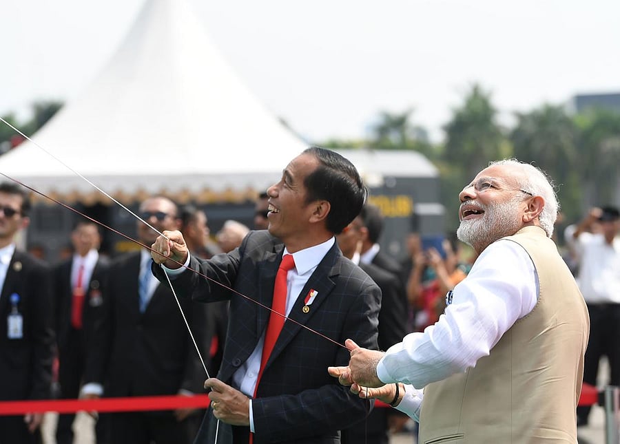 This handout photograph taken and released by India's Press Information Bureau (PIB) on May 30, 2018 shows Indian Prime Minister Narendra Modi (R) and Indonesian President Joko Widodo (C) laugh as they fly kites at the India-Indonesia Kite Exhibition in J