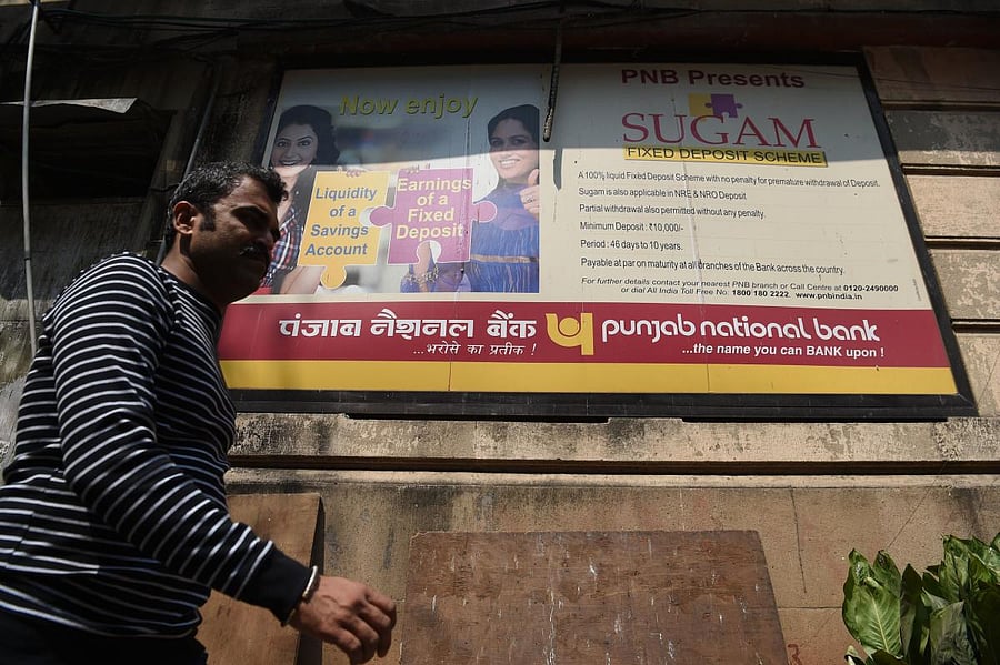 A man walks past a sign for Punjab National Bank in Mumbai. AFP