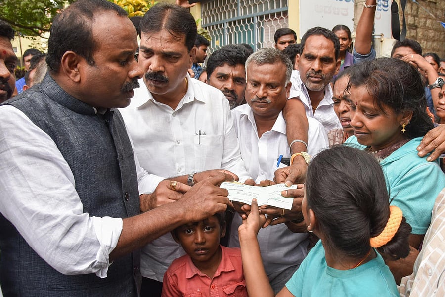 Mayor Sampath Raj hands over a cheque for 5 lakh to the wife of S Subramani at the KC General Hospital on Monday. dh Photo 