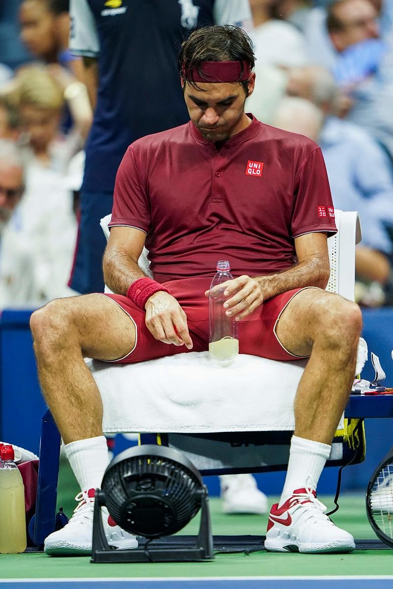 NOT EASY: Switzerland's Roger Federer uses a fan to cool off during his fourth round game against John Millman of Australia. AFP