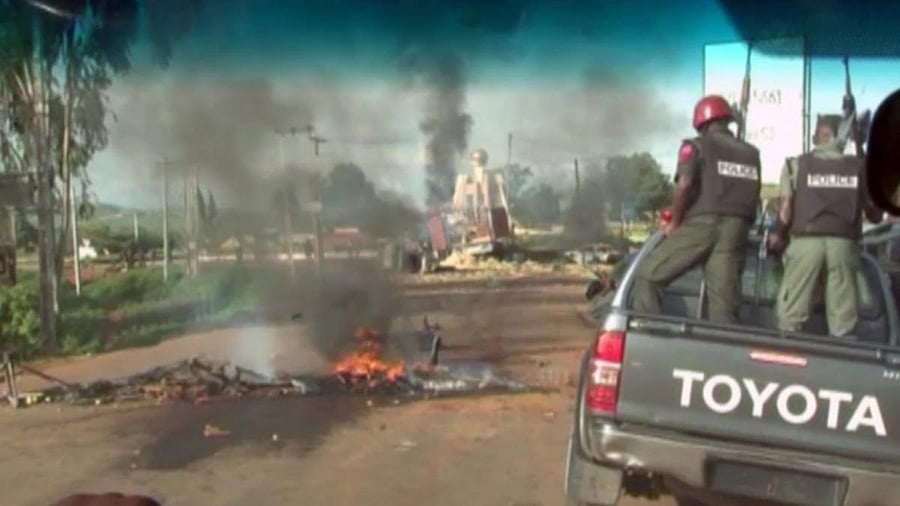 A bonfire and overturned vehicles block the road as police attempt to restore calm, in the town of Jos, Nigeria, Sunday June 25, 2018. Some scores of people are reported to have died during weekend clashes in central Nigeria between mostly Muslim herders