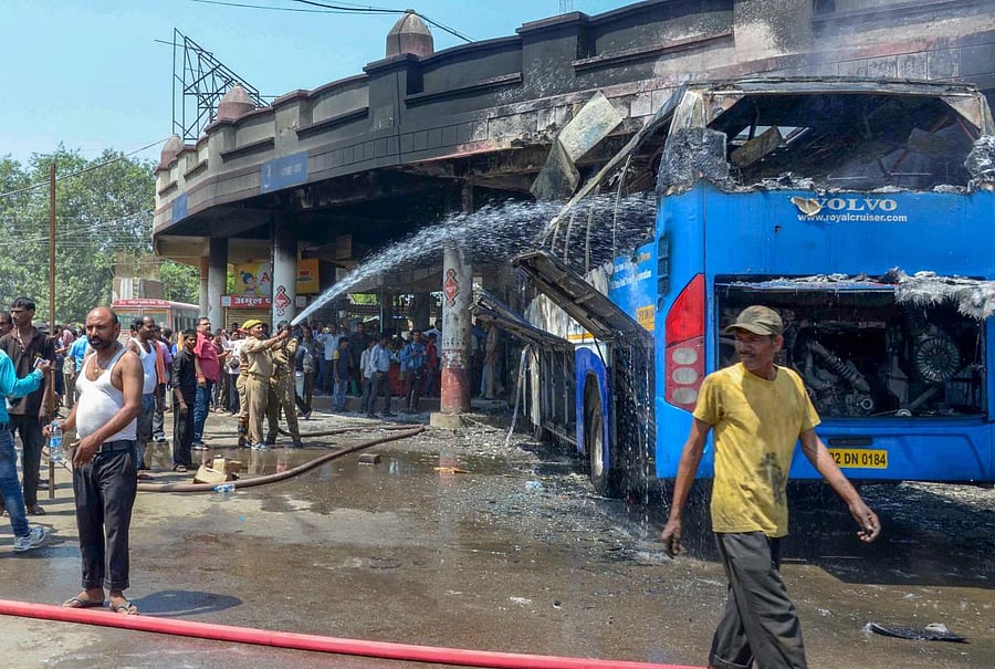 Firefighters douse a fire at a roadways bus that was reportedly torched by a woman protester during a protest for the separate state of 'Purvanchal', in Varanasi on Wednesday. PTI
