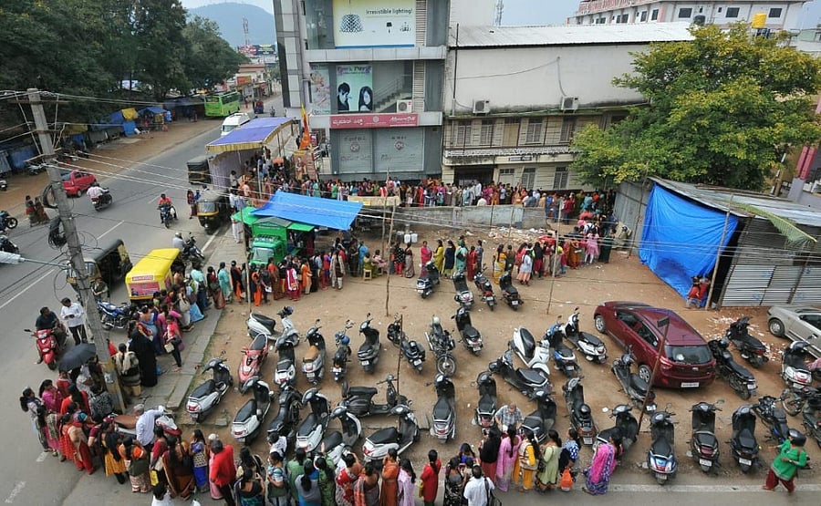 People queue up in front of the Mysuru Silk showroom, near Sri Chamarajendra Zoological Gardens, in Nazarbad, Mysuru, on Tuesday. (DH Photo by K S Gireesha)