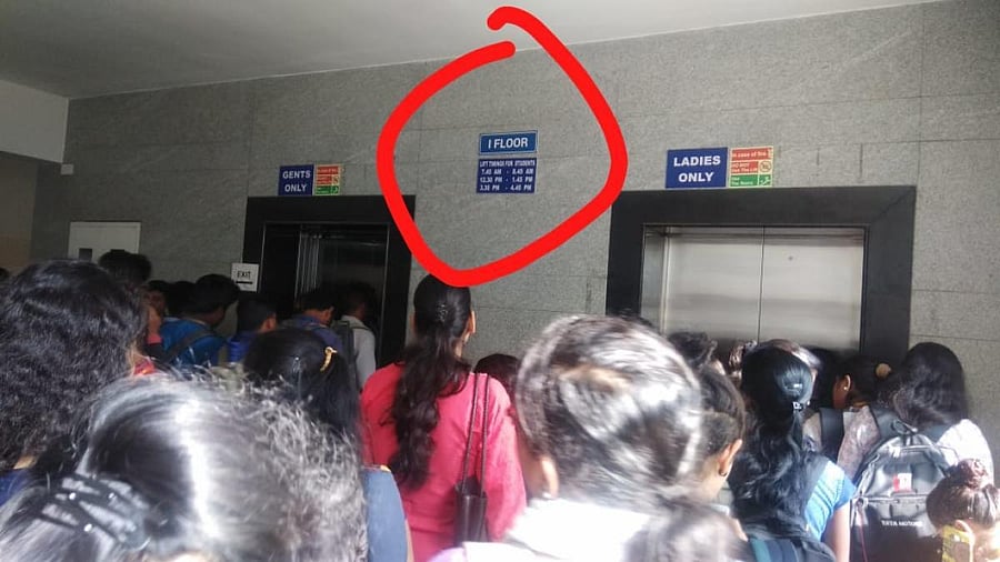 The board displaying the time schedule to use the lift in the background as students rush to take the lift. DH Photo