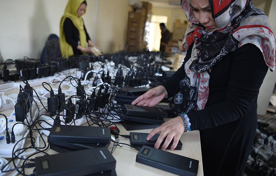 Afghan employees of the Independent Election Commission (IEC) charges power bank devices at a warehouse in Kabul. (AFP file photo)