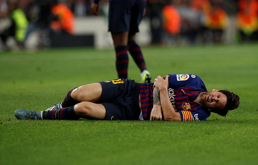 BIG BLOW Barcelona striker Lionel Messi writhes in pain after hurting his right arm during their La Liga clash against Sevilla in Barcelona on Saturday. Reuters