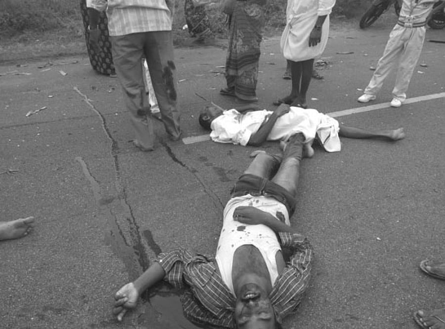 People stand next to the accident victims at the spot where the mishap took place near Sattarupalli in Anantapur district, Andhra Pradesh.