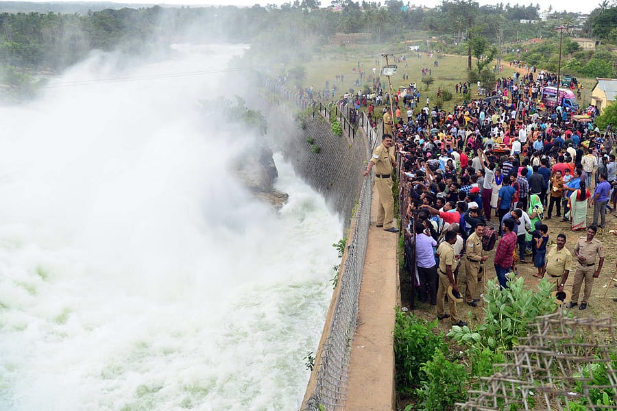 Tourists take a glimpse of water gushing out of the KRS damin Srirangapatna taluk, Mandya district, on Sunday. DH PHOTO