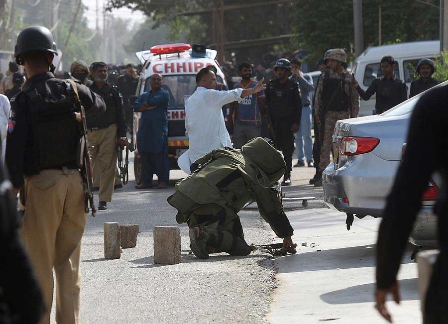 A bomb disposal squad member checks a bag belonging to an attacker outside the Chinese consulate after the attack in Karachi on November 23, 2018. - At least two policemen were killed when unidentified gunmen stormed the Chinese consulate in the Pakistani port city of Karachi on November 23, officials said. (Photo by ASIF HASSAN / AFP)