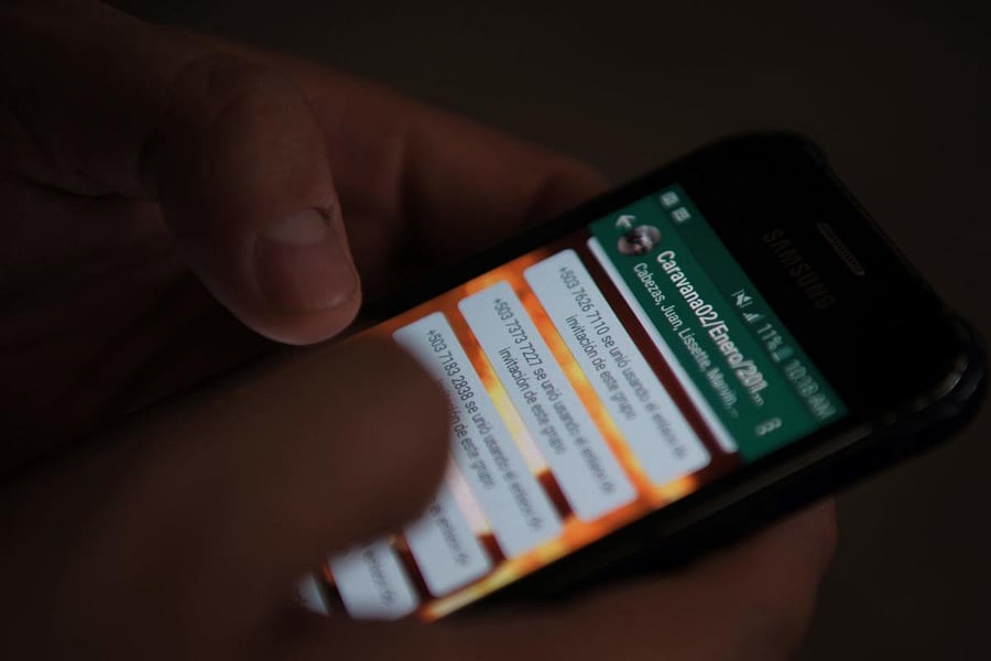 A man navigates in his mobile phone in a group in which Salvadoran migrants organize a caravan to the United States, in San Salvador. AFP