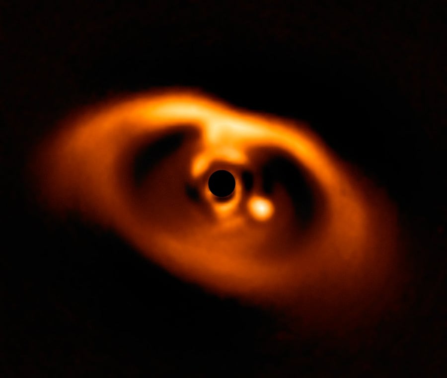 This spectacular image from the SPHERE instrument on ESO's Very Large Telescope is the first clear image of a planet caught in the very act of formation around the dwarf star PDS 70. The planet stands clearly out, visible as a bright point to the right of the centre of the image, which is blacked out by the coronagraph mask used to block the blinding light of the central star. ESO/A. Müller et al. ESO/A. Müller et al.