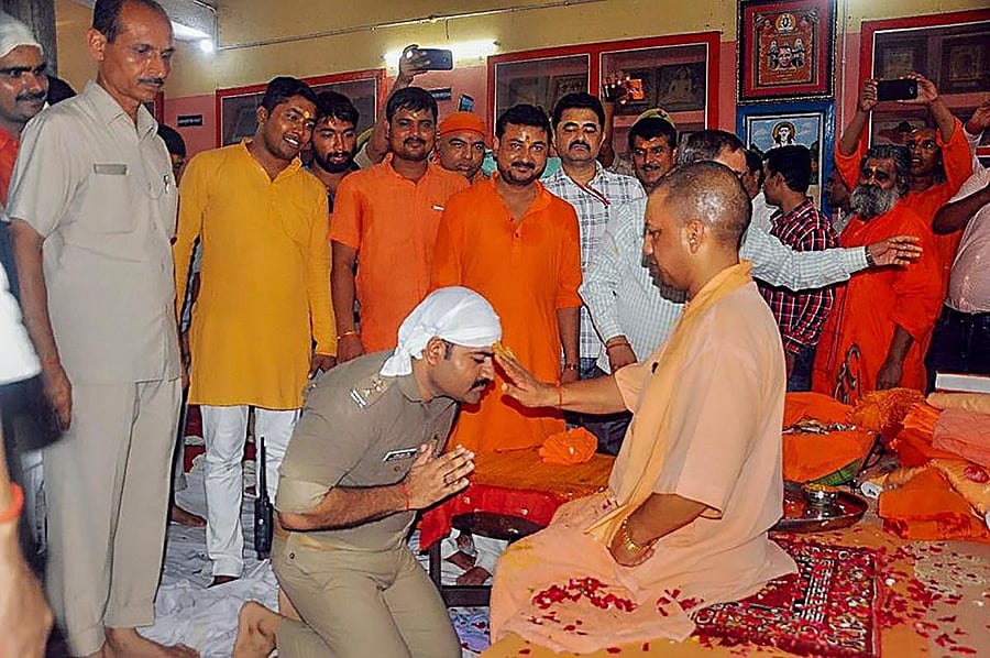 A police officer in uniform kneels down at the feet of Uttar Pradesh Chief Minister Yogi Adityanath, on the occasion of Guru Purnima at the Gorakhnath temple, in Gorakhnath on Friday. PTI