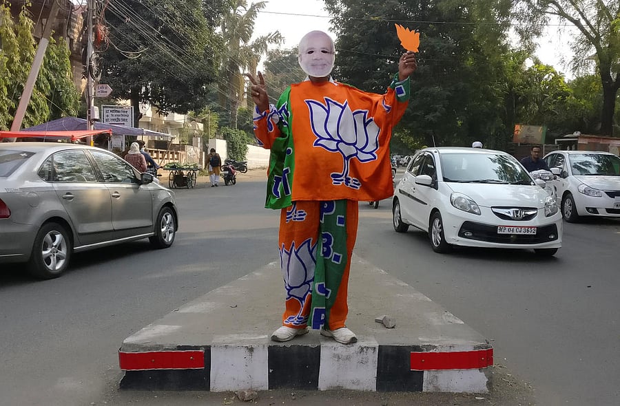 REFILE - REMOVING ERRONEOUS INFORMATION A supporter of India's Bharatiya Janata Party (BJP) wears a mask depicting the Indian Prime Minister Narendra Modi, and drapes himself with flags of BJP's symbol at a traffic signal in Bhopal, India, November 20, 20