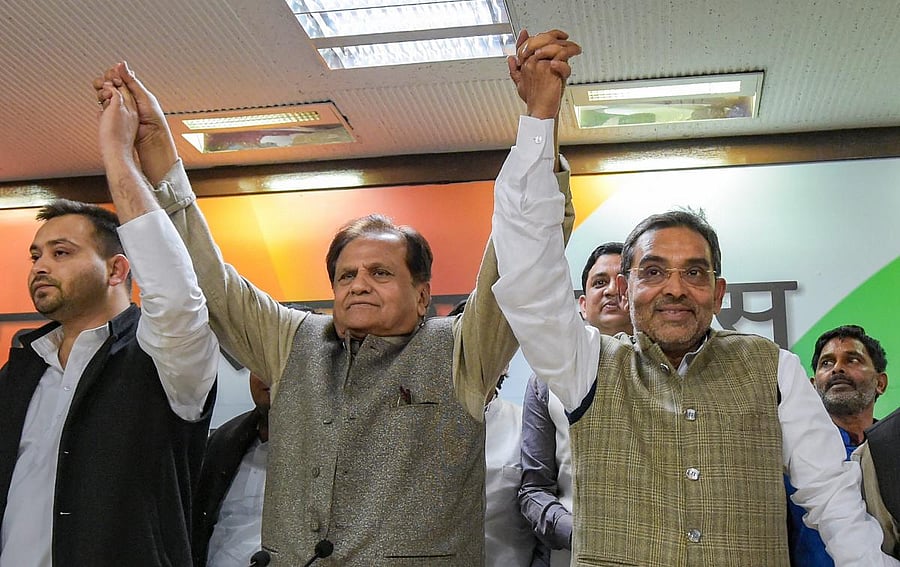 Rashtriya Lok Samta Party (RLSP) leader Upendra Kushwaha (R) raises hands with others Congress party's Ahmed Patel and RJD's Tejashwi Yadav after joining the grand alliance during a press conference at AICC in New Delhi. (PTI Photo)