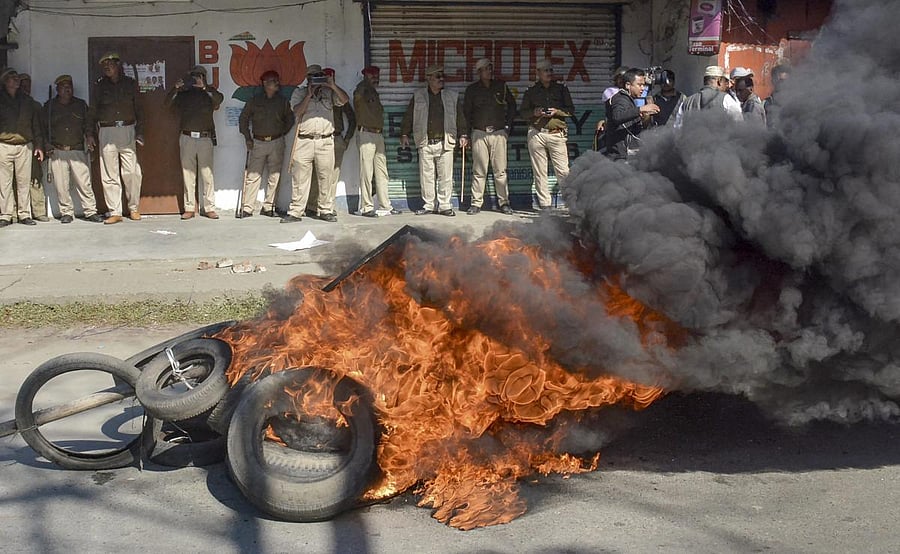 Police personnel look on as tyres are seen ablaze during a strike called by All Assam Students’ Union (AASU) and the North East Students’ Organisation (NESO) in protest against Citizenship (Amendment) Bill, in Dibrugarh. PTI Photo