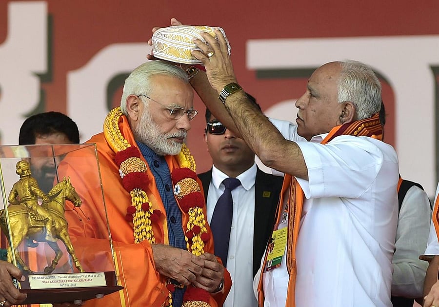 Prime Minister Narendra Modi being presented a Mysore Peta by State President B S Yeddyurappa during the Parivartan Yatra rally in Bengaluru. PTI