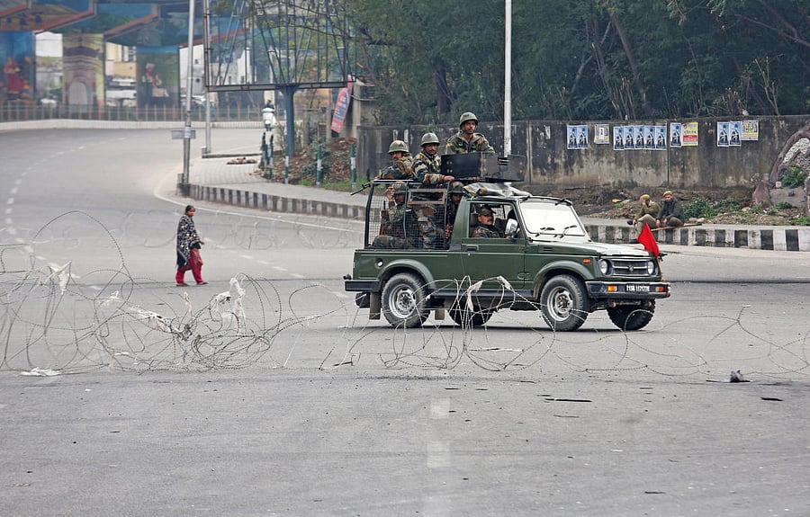 Indian Army soldiers in a vehicle patrol a street as a woman walks past during a curfew in Jammu, February 17, 2019. REUTERS/Mukesh Gupta