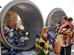 homeless: Residents of Ejipura seek refuge in cement pipes, with their children and the few belongings they could save  during the demolition drive. DH Photos