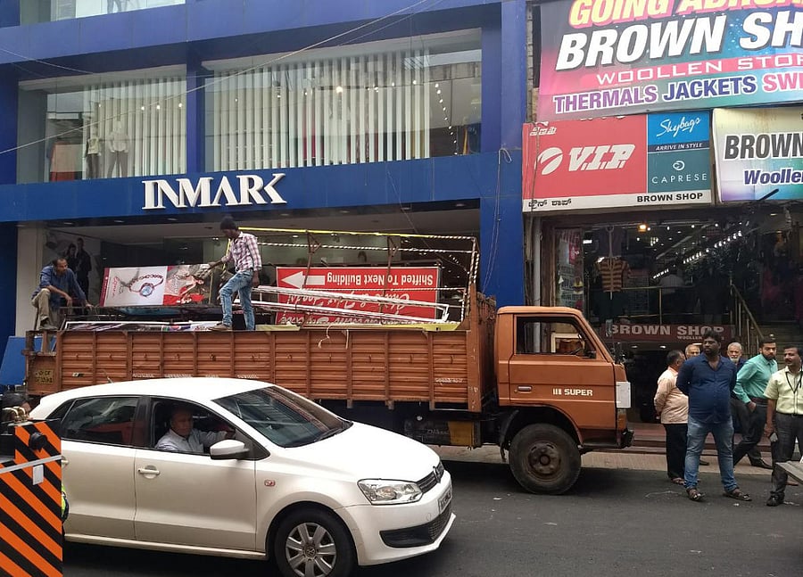 BBMP Contract workers are removing the projected and unauthorised and violating the norms sign boards (Name boards ), at Commercial street in Bengaluru on Tuesday. DH Photo