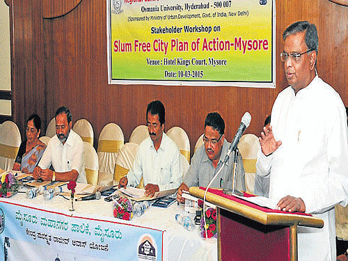 Revenue and District in-charge Minister V Srinivas Prasad addresses the gathering during the stakeholder meet on Slum Free City Plan of Action, in Mysuru, on Tuesday. Mayor R Lingappa, Deputy Mayor Mahadevamma, MLAs Vasu and Tanveer Sait are seen. DH Photo