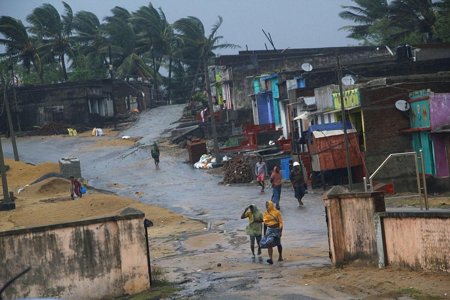 Locals walk near their houses as Cyclone 'Titli' hits the coast, in Ganjam. The "very severe" cyclonic storm left eight people dead, besides causing widespread damage in north coastal Andhra Pradesh Thursday, the State Disaster Management Authority (SDMA)