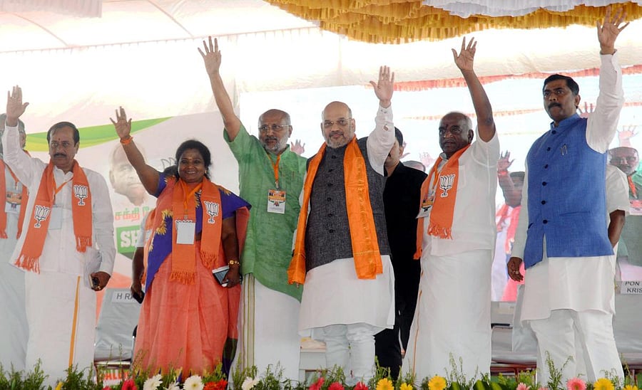 BJP National President Amit Shah waves at the gathering during a meeting of Handloom & Powerloom Associations in Erode, Tamil Nadu, Thursday, Feb 14, 2019. BJP Union Minister Pon Radhakrishnan (2nd R) is also seen. (Handout Photo via PTI)