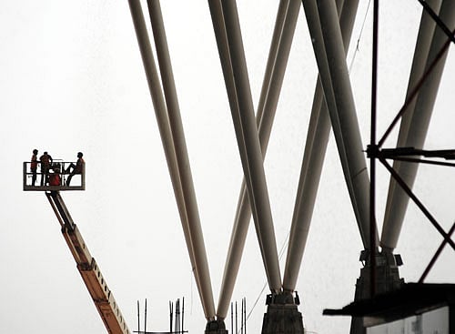 A group of workers seen busy on heavy ladder crane to construct the extension roof for the Bangalore International Airport (BIA) in Bangalore on Tuesday. DH Photo by Satish Badiger