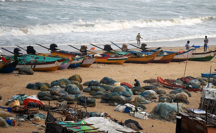 Fishermen stand along a beach beside fishing boats on the coast of the Bay of Bengal, in Chennai. Cyclone 'Gaja' is forecasted to make a landfall between Chennai and Nagapattinam on Thursday evening. (AFP FILE PIC)
