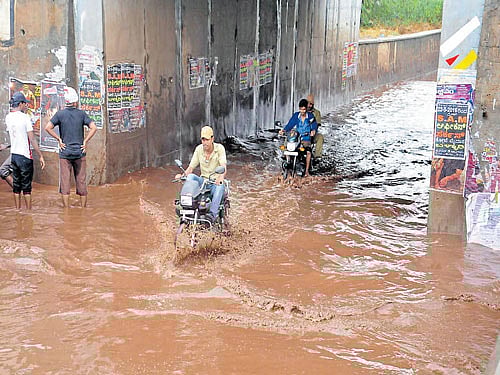 Motorcyclists struggle through a waterlogged underpass in Ballari on Sunday. DH Photo