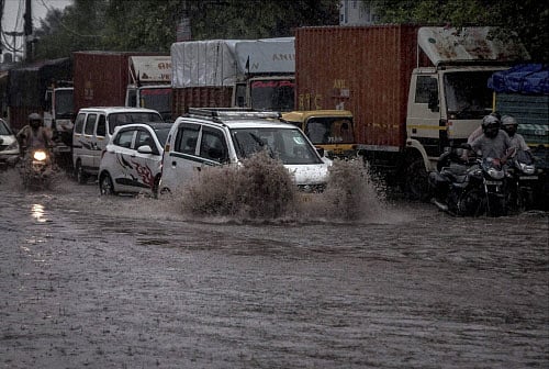 Vehicles make their way through floodwaters on a street during heavy rain in New Delhi on Friday. PTI Photo